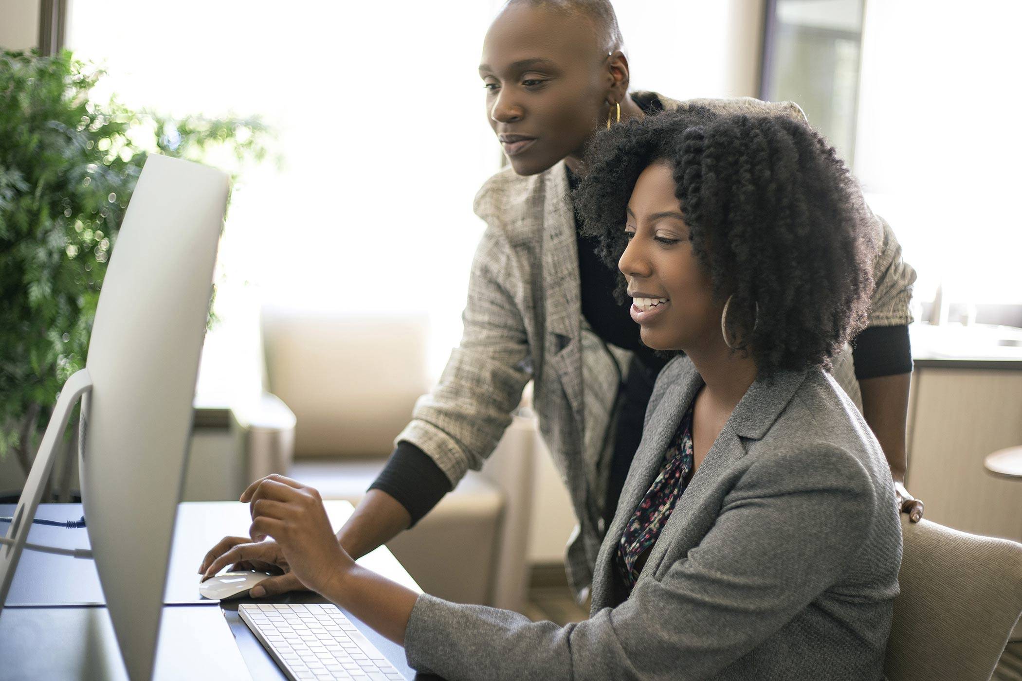 Black African American businesswomen or coworkers together in an office doing teamwork or job training.