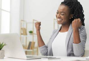 Woman Celebrating Business Success Sitting At Laptop In Office