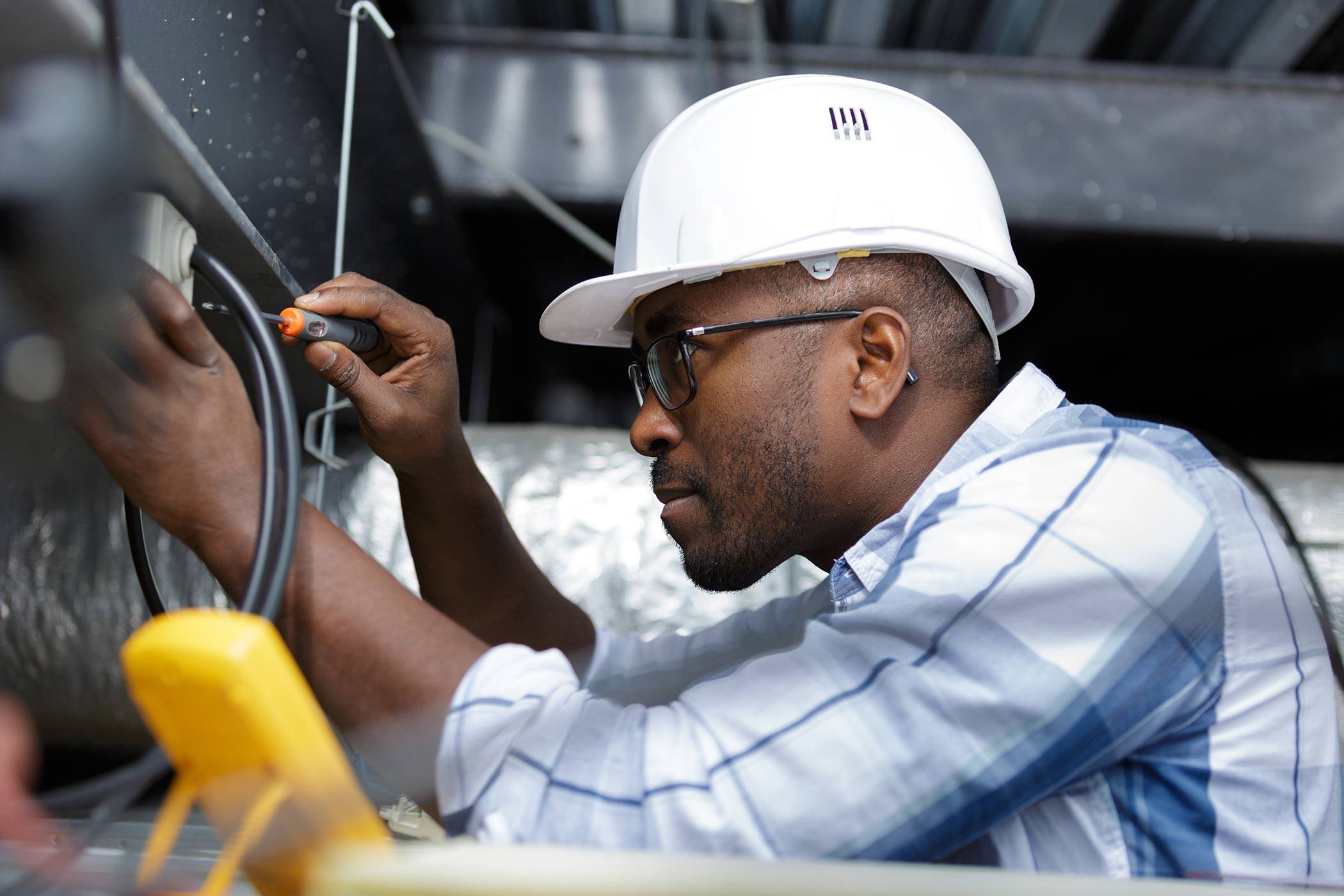 Black male electrician working on wiring.