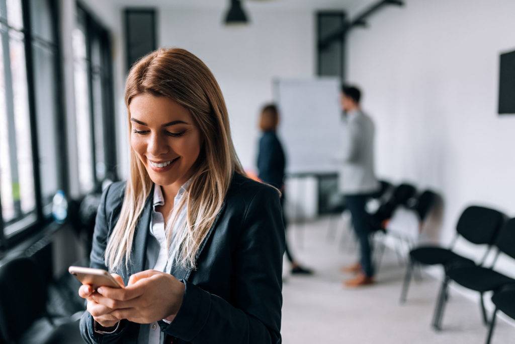 Happy woman texting on cell phone after successful job interview